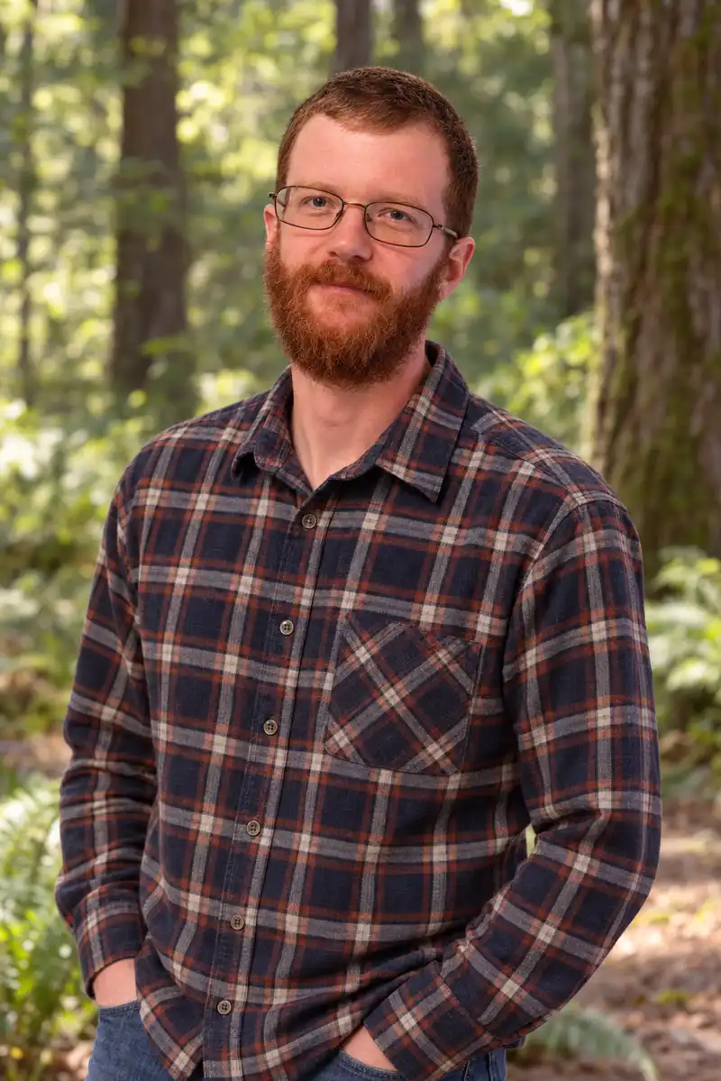 Taylor Guynes, ISA Certified Arborist TX-433A, standing among mature trees; he writes the tree assessments Legacy Tree Care delivers on commercial property in Plano, TX.